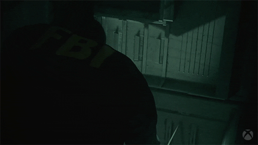 Agente de policía levantanto un corazón del suelo en una habitación oscura del nuevo juego Alan Wake 2.- Blog Hola Telcel